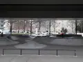 Ein leerer Berlin Skatepark unter einer Brücke. Ein Radfahrer fährt durch die Betonlandschaft.