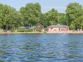 Sommerfreuden am See in Berlin: Menschen planschen im Wasser, entspannen am Strand und genießen die Sonne.