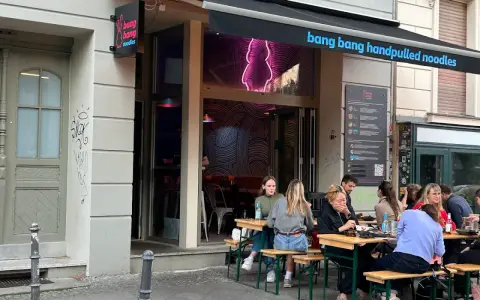 Menschen genießen das Essen vor dem Restaurant "bang bang noodles berlin".