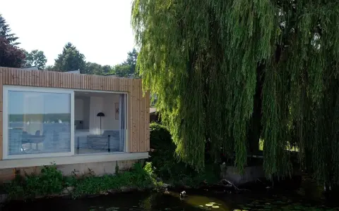 Modernes Haus am Wannsee Berlin mit großem Fenster und Weidenbaum.