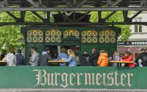 Menschen sitzen an Tischen vor dem Burgermeister in Berlin.