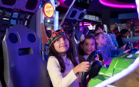 Kinder mit Kronen auf dem Kopf spielen in einer Spielhalle in Berlin Rennspiele.