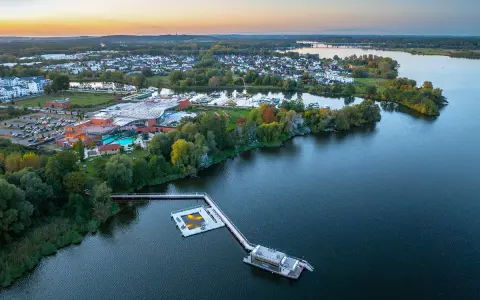 Luftaufnahme der Havel Therme mit einem schwimmenden Pool auf dem Wasser. Ein idyllisches Bild der Entspannung am See.