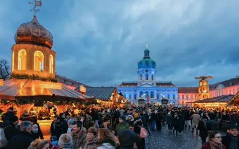 Besucher genießen den Weihnachtsmarkt vor dem beleuchteten Schloss Charlottenburg in Berlin.