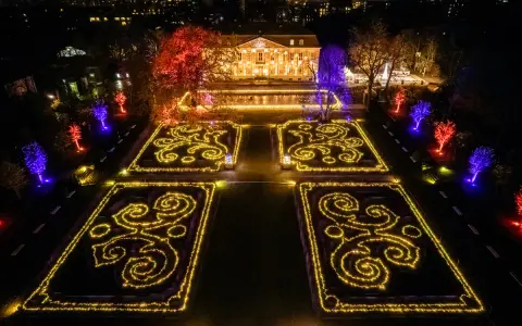 Magische Lichtershow im Tierpark Berlin: Verzauberte Gärten mit leuchtenden Mustern und farbig beleuchteten Bäumen vor einem prachtvollen Gebäude.
