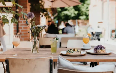 Leckeres Frühstück im 21 gramm Berlin: Toast mit Belag, Drinks & Blumen auf Holztisch.