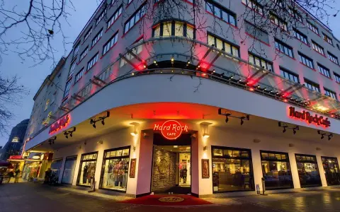 Das Hard Rock Cafe Berlin erstrahlt im Abendlicht. Rote Neonschilder und Beleuchtung werfen einen warmen Schein auf die Fassade des Gebäudes.