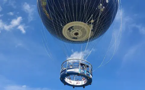 Weltballon über Berlin bei schönem Wetter. Die Gondel mit Passagieren schwebt unter dem riesigen Globus-Ballon.