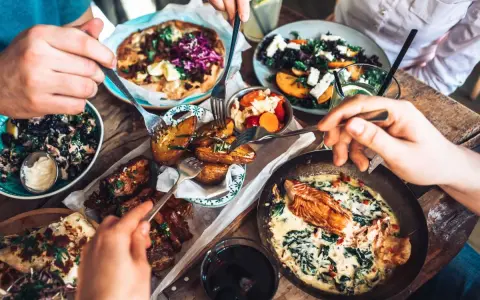 Leckeres Essen in einem Restaurant in Berlin Mitte: Pizza, Lachs, Rippchen und Salate werden von mehreren Händen geteilt.