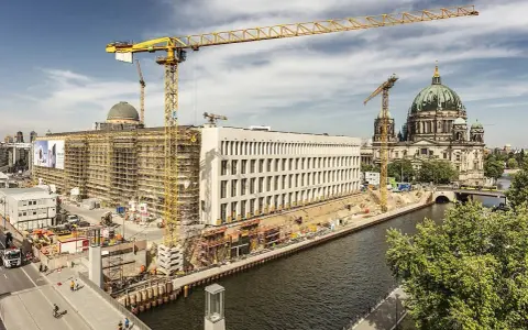 Baustelle am Berliner Dom, Kräne ragen in den Himmel. Ein neues Gebäude entsteht, während der Dom in seiner Pracht erstrahlt. Ein Blick auf das heutige Berlin, das sich ständig neu erfindet.