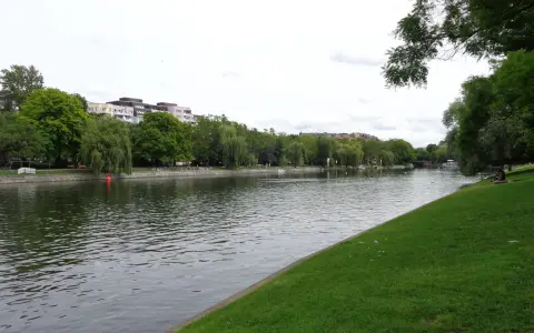 Grüne Ufer am Landwehrkanal Berlin mit Bäumen, Gebäuden und Menschen, die sich auf der Wiese entspannen.