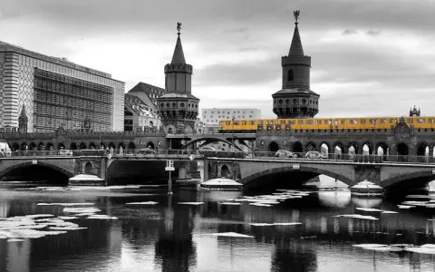 Gelbe U-Bahn fährt über die Oberbaumbrücke in Berlin. Eisschollen treiben auf dem Wasser.