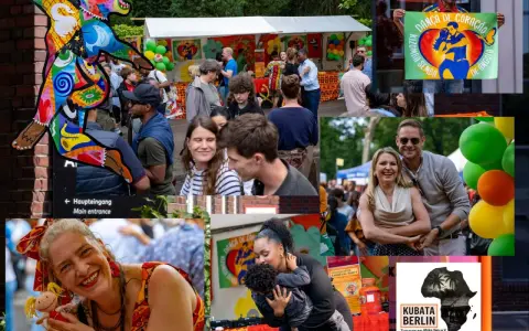Bunte Kunstfigur und fröhliche Menschen beim **Carnival Berlin**. Ein Mann hält ein Plakat mit der Aufschrift "Danza de Coração".
