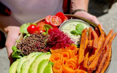 Ein bunter Buddha Bowl mit Avocado, Quinoa, Süßkartoffel-Pommes und Karottenrosen. Ein froindlichst Berlin-Genuss!
