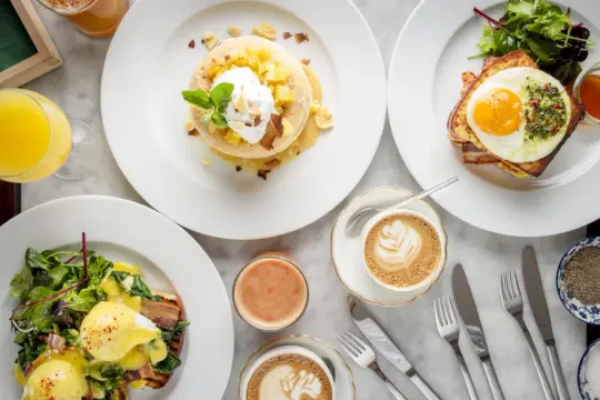 Ein köstlicher Brunch in Berlin: Pancakes mit Früchten, Eggs Benedict und Croque Madame mit Spiegelei. Dazu Kaffee und Saft.