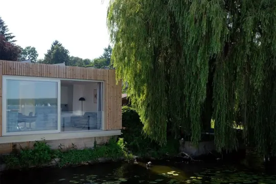 Modernes Haus am Wannsee Berlin mit großem Fenster und Weidenbaum.