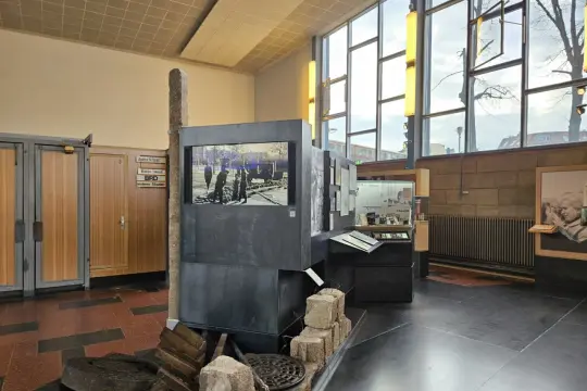 Ausstellung im "Palace of Tears" Berlin: Ein Stein, ein Bildschirm mit historischem Bild, und Ausstellungsstücke erinnern an die Teilung.