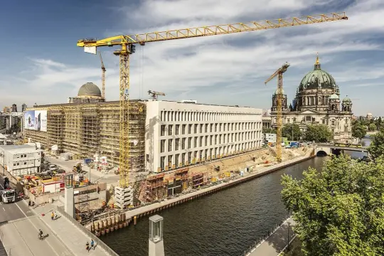 Baustelle am Berliner Dom, Kräne ragen in den Himmel. Ein neues Gebäude entsteht, während der Dom in seiner Pracht erstrahlt. Ein Blick auf das heutige Berlin, das sich ständig neu erfindet.