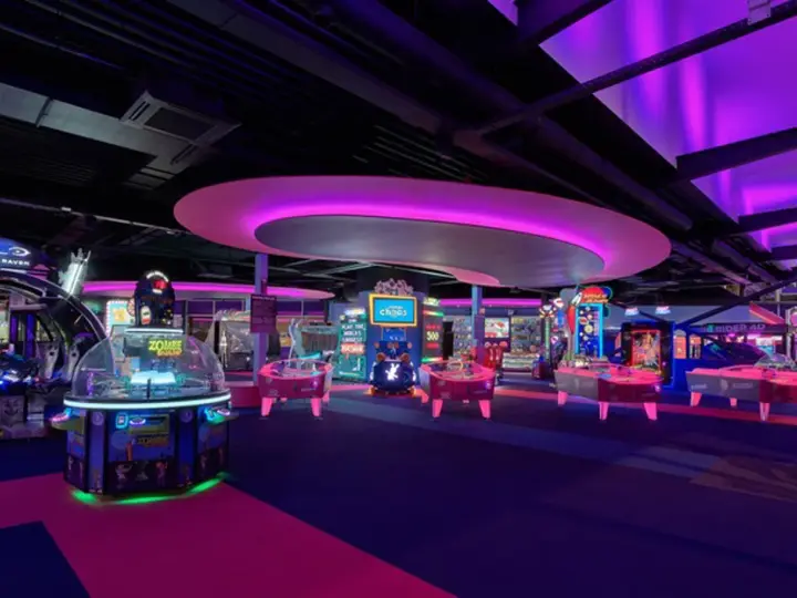 Bunte Spielautomaten und Air-Hockey-Tische in einem beleuchteten Gamestate Potsdamer Platz.