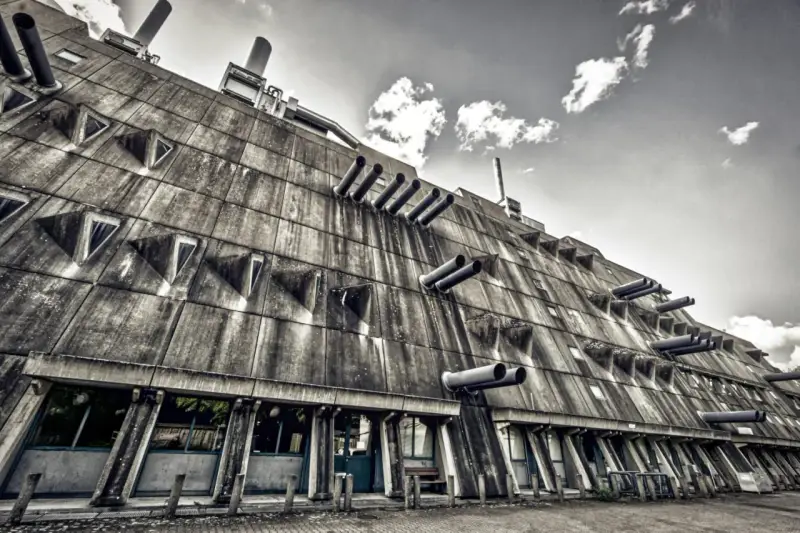 Betonriese im **Brutalismus Berlin**: Eine Fassade mit dreieckigen Fenstern und Rohren, die wie Kanonen aussehen.