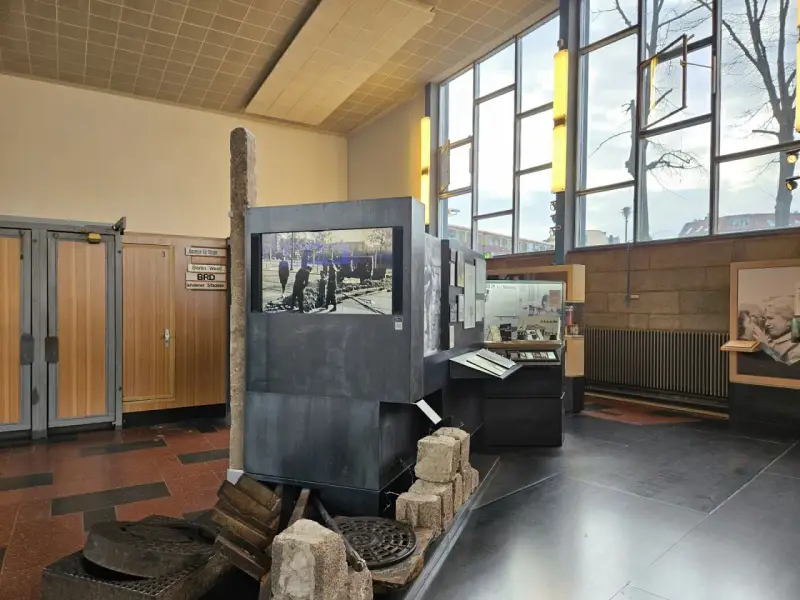 Ausstellung im "Palace of Tears" Berlin: Ein Stein, ein Bildschirm mit historischem Bild, und Ausstellungsstücke erinnern an die Teilung.