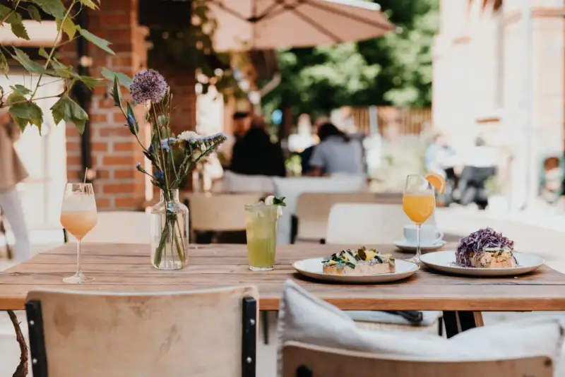Leckeres Frühstück im 21 gramm Berlin: Toast mit Belag, Drinks & Blumen auf Holztisch.