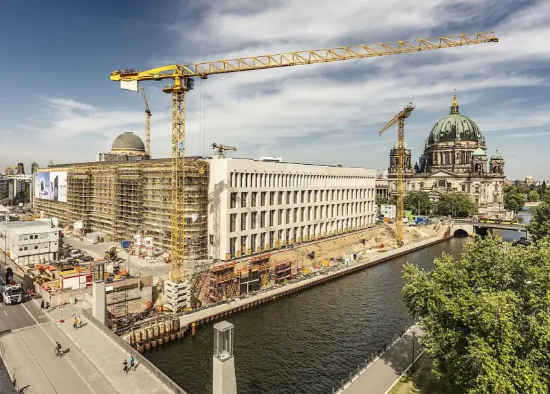Baustelle am Berliner Dom, Kräne ragen in den Himmel. Ein neues Gebäude entsteht, während der Dom in seiner Pracht erstrahlt. Ein Blick auf das heutige Berlin, das sich ständig neu erfindet.